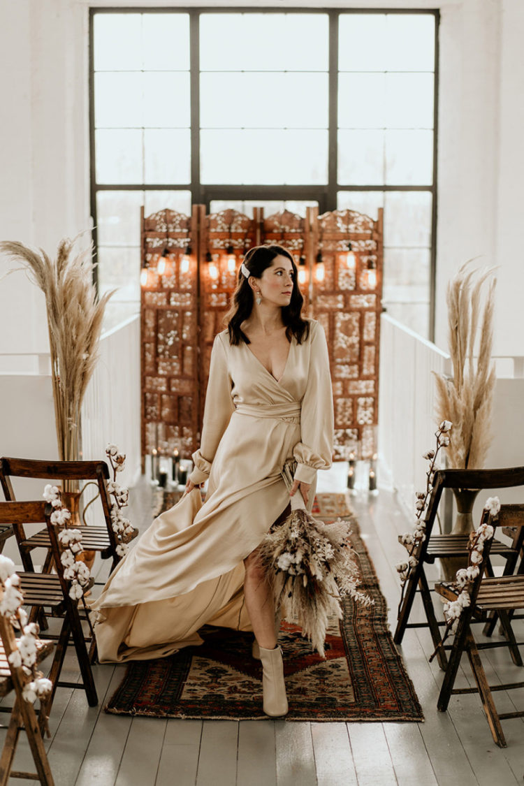 The bride was wearing a neutral silk wrap wedding dress, booties and carrying a chic bouquet