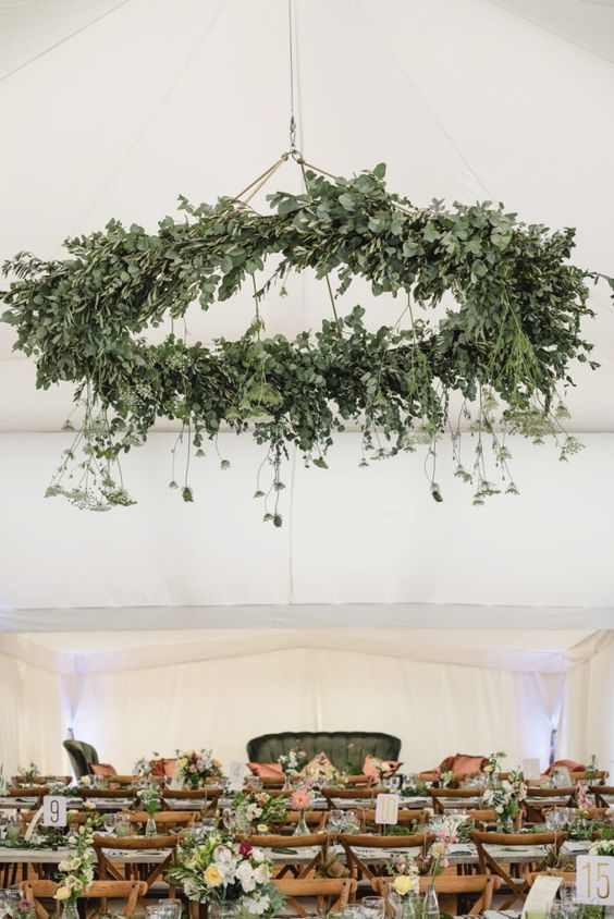 a statement greenery chandelier with hanging elements takes over the whole reception space