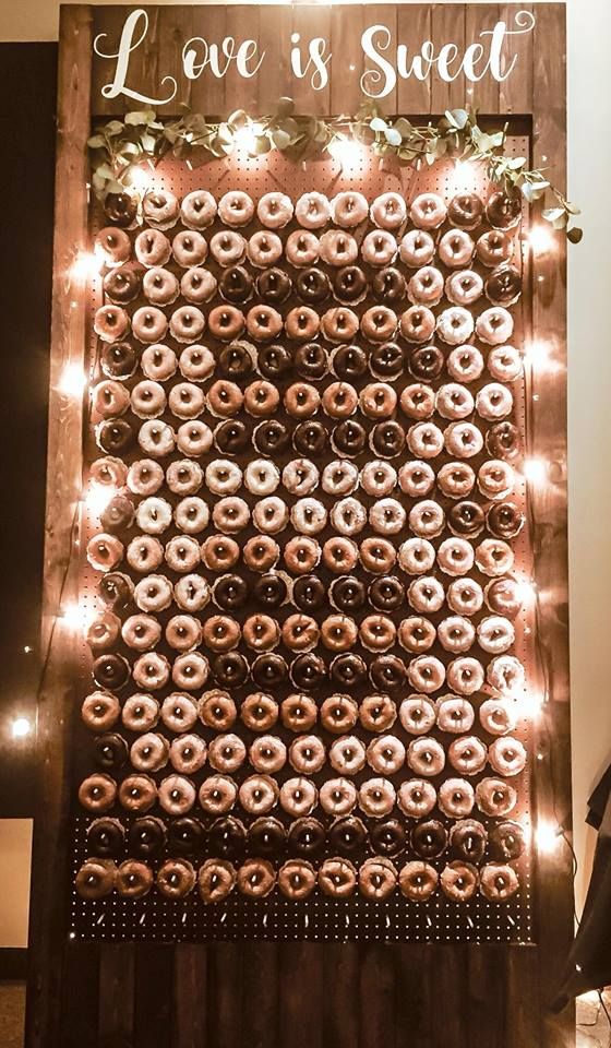 a chic donut wall with lights, greenery and white calligraphy for a stylish rustic wedding