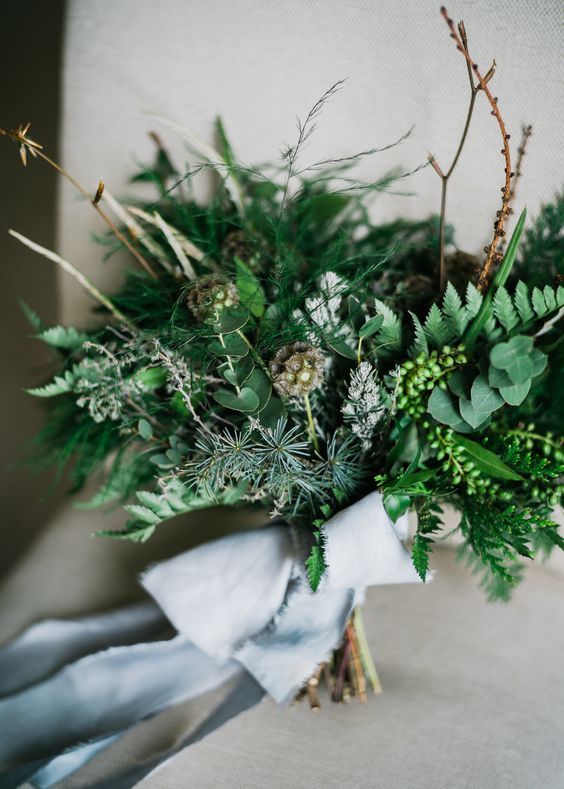 a lush and textural greenery wedding bouquet and twigs plus blue ribbons is a chic idea