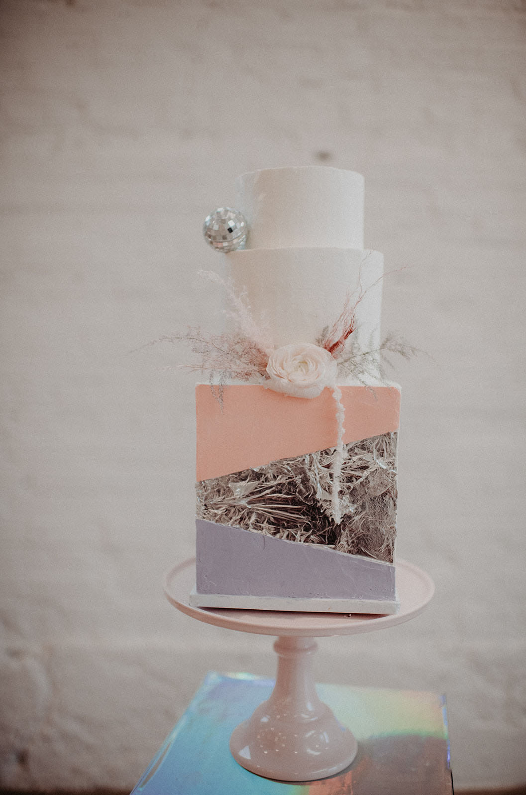 The wedding cake is a masterpiece in white, pink, lilac and silver leaf plus disco balls and blooms