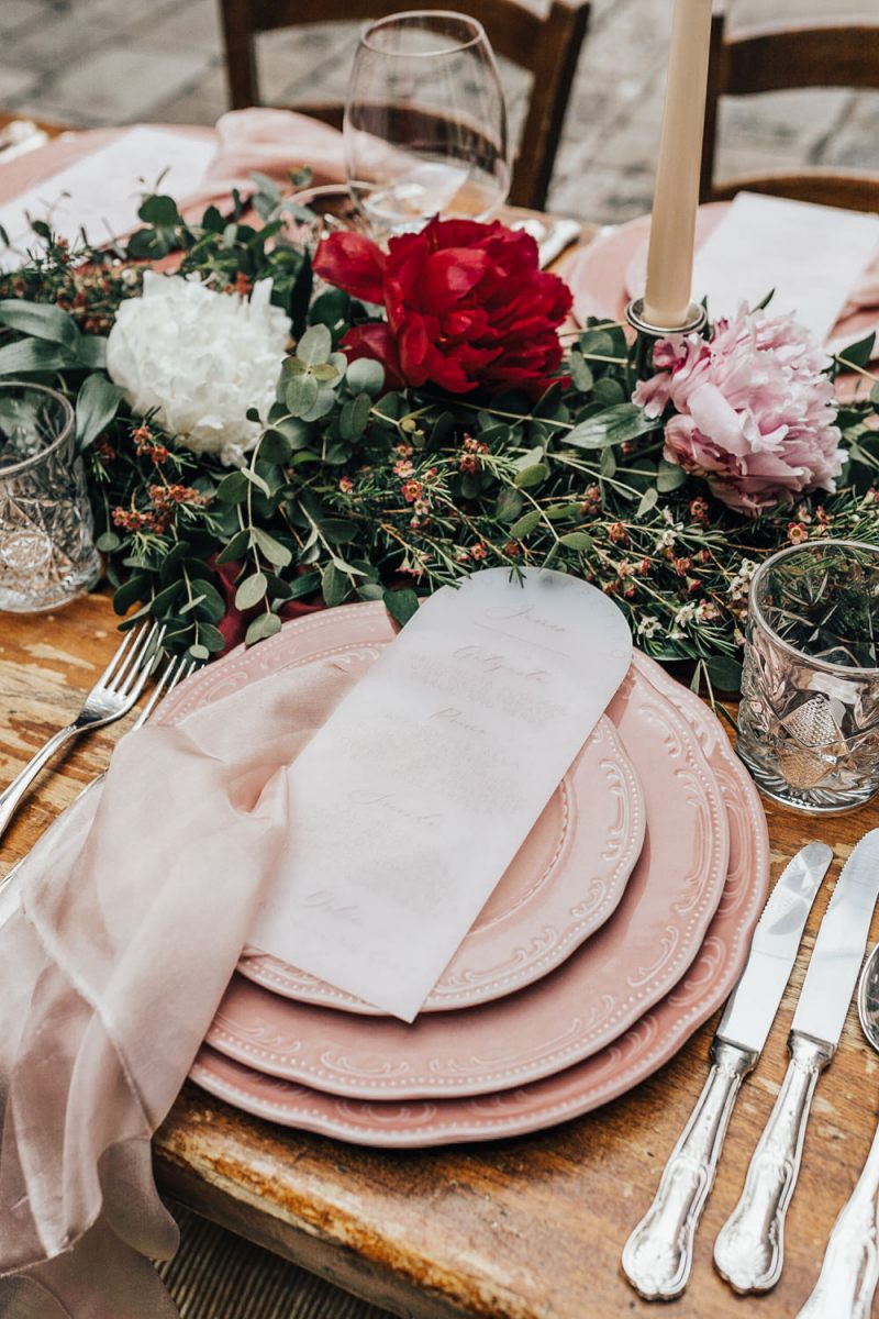 The wedding tablescape was done with pink plates, lush greenery and bold blooms