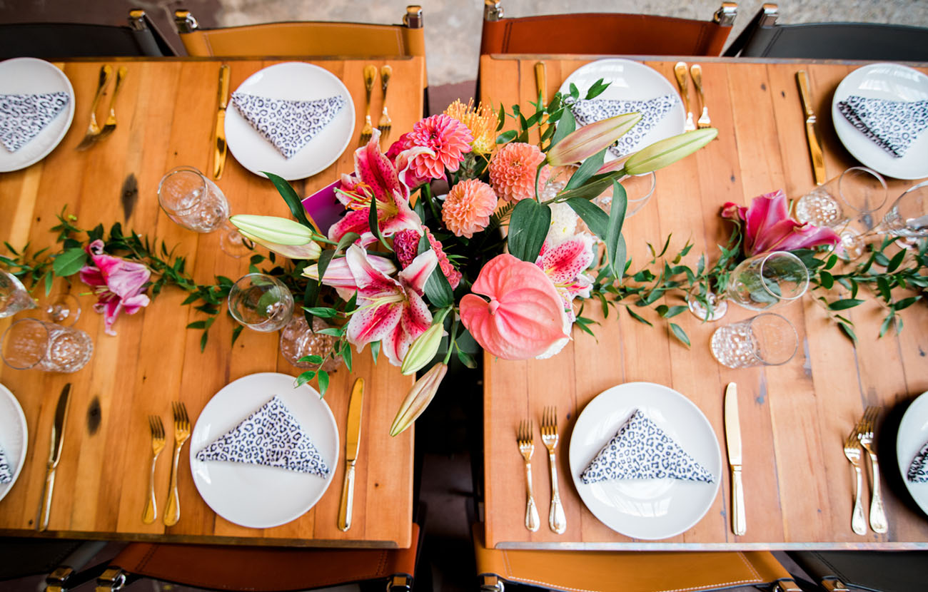 bright reception tables done with colorful florals and leopard print napkins plus ggold cutlery for more elegance