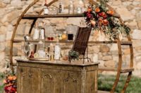 19 a chic rustic bar with a vintage sideboard, a round part with lots of bottles and blooms