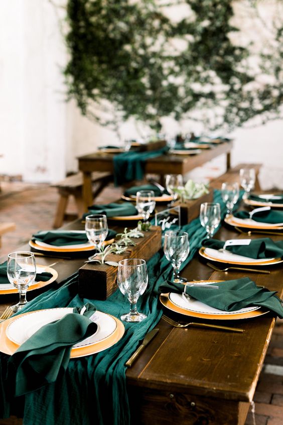 a simple and modern wedding tablescape with emerald linens, greenery and metallic touches
