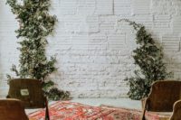 a simple micro wedding ceremony space with greenery, boho rugs and wooden chairs