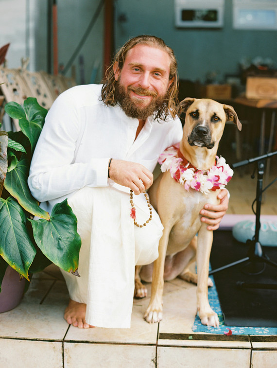 The groom was wearing a white shirt and pants, the dog was dressed up in a floral collar