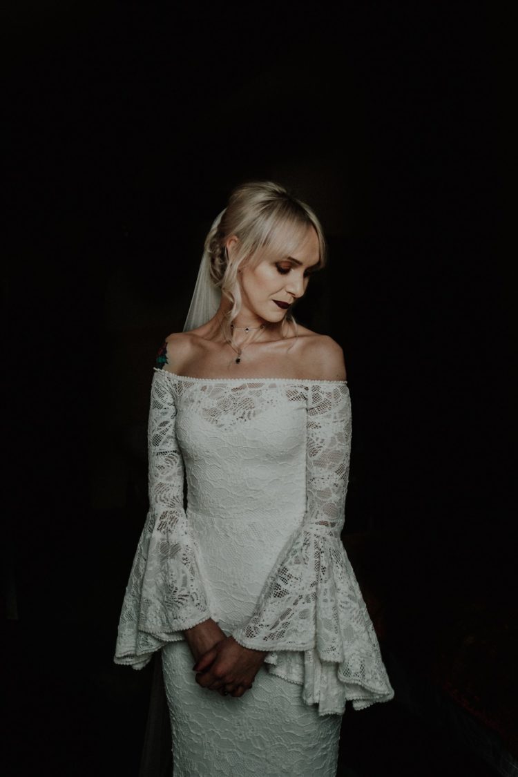 The bride was an off the shoulder lace sheath wedding dress with bell sleeves and a dark lipstick