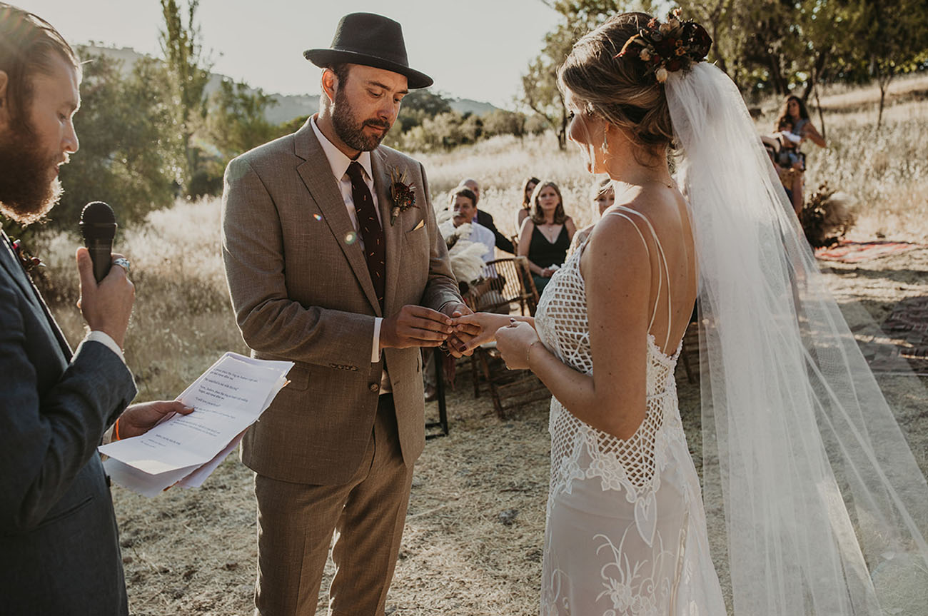 The groom was rocking a tan suit, a burgundy printed tie, a black hat