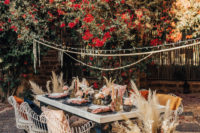 06 The wedding reception space was quirky and bold, with candle lanterns and pampas grass, blush blooms, black and dark chargers and cool chairs