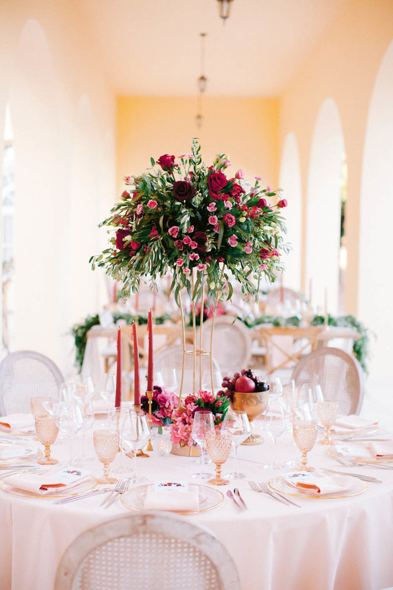 The sweetheart table was done with a lush and tall bold floral centerpiece with greenery, fruits and blooms and colorful candles