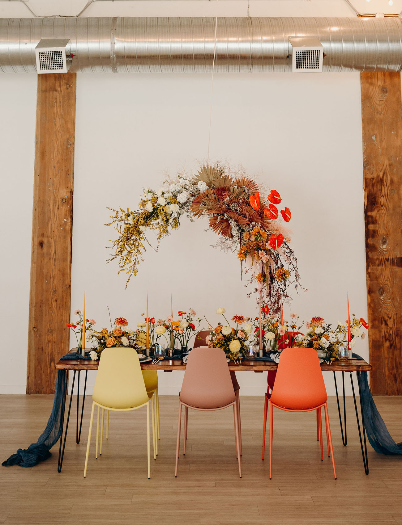 The wedding reception was done with a large overhead floral installation with dried leaves, with bright blooms on the table and a navy runner