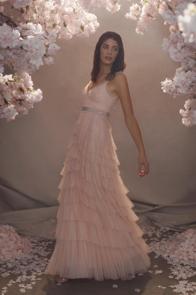 A romantic pink wedding dress with ruffle straps and a necklace, a tiered tulle skirt and an embellished sash