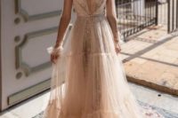 25 a tan embellished wedding dress with a plunging neckline, a tiered tulle skirt and a sheer overdress