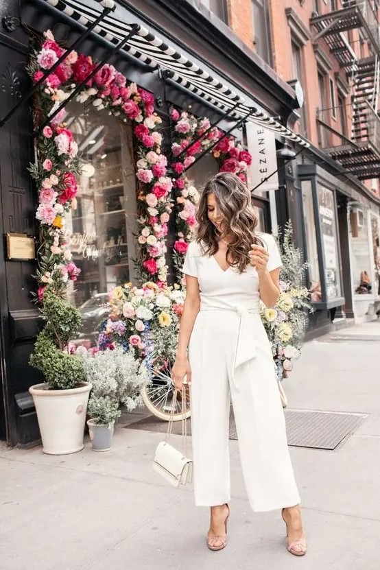 a casual white jumpsuit with a V-neckline, short sleeves, wideleg pants, nude shoes and a white bag