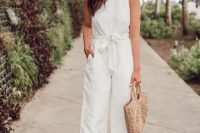 a casual white jumpsuit with wideleg pants, a high neckline and no sleeves, nude shoes and a woven bag for summer