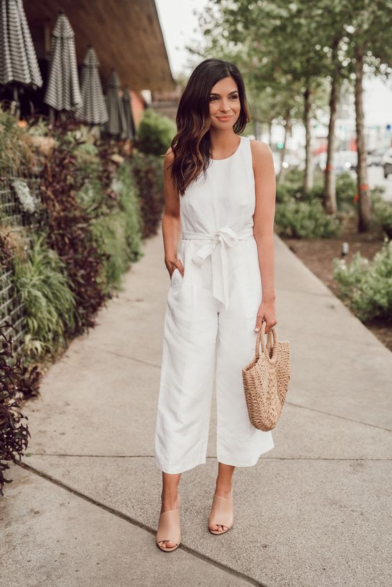 a casual white jumpsuit with wideleg pants, a high neckline and no sleeves, nude shoes and a woven bag for summer