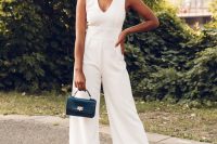 a chic and cool white jumpsuit with a V-neckline, no sleeves, wideleg pants, nude shoes and a small black bag