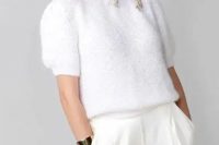 a white knit top with short sleeves, white high waisted wideleg trousers, statement silver earrings and a bracelet for a modern casual look