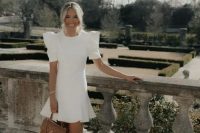 a white mini dress with a high neckline, puff sleeves and a ruffle edge, nude shoes and a brown bag for a bridal shower