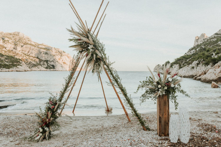 This teepee was renovated into an arch with greenery, blooms and pampas grass plus an altar with an arrangement