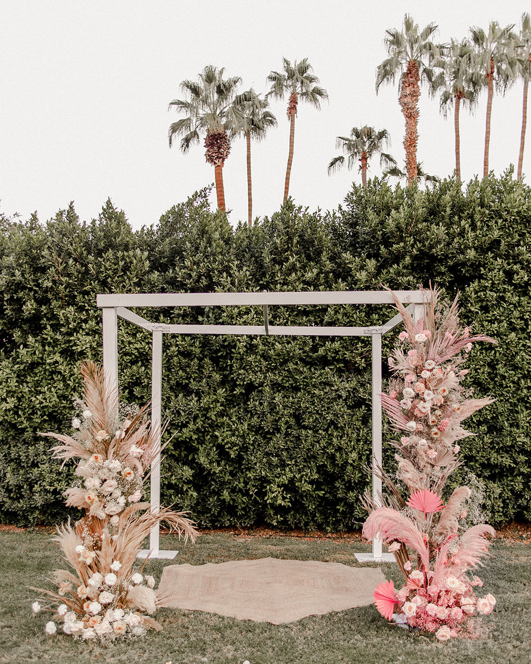 The wedding arch was done with pink fronds, pampas grass and blush blooms