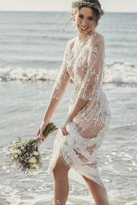 a sheer wedding gown with floral embroidery, a high neckline and long sleeves for beach bride