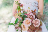 a beautiful and romantic wedding bouquet with pink and peachy roses, greenery and smoke bush looks trendy at the same time