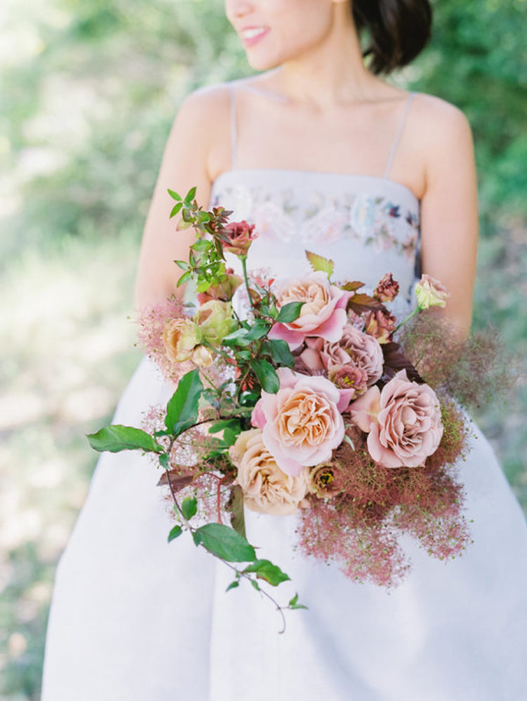 a beautiful and romantic wedding bouquet with pink and peachy roses, greenery and smoke bush looks trendy at the same time