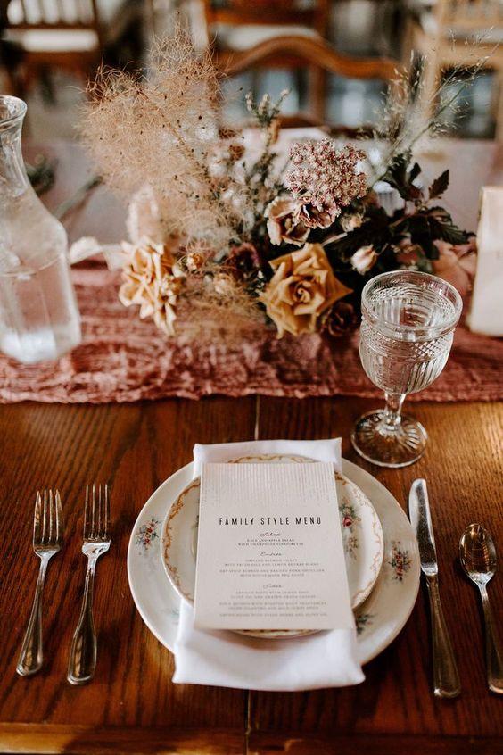 a refined wedding centerpiece with pink and rust blooms, dark leaves and smoke bush for a fall wedding