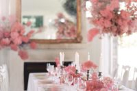 a refined wedding reception table with pink blooms and smoke bush on it and over it