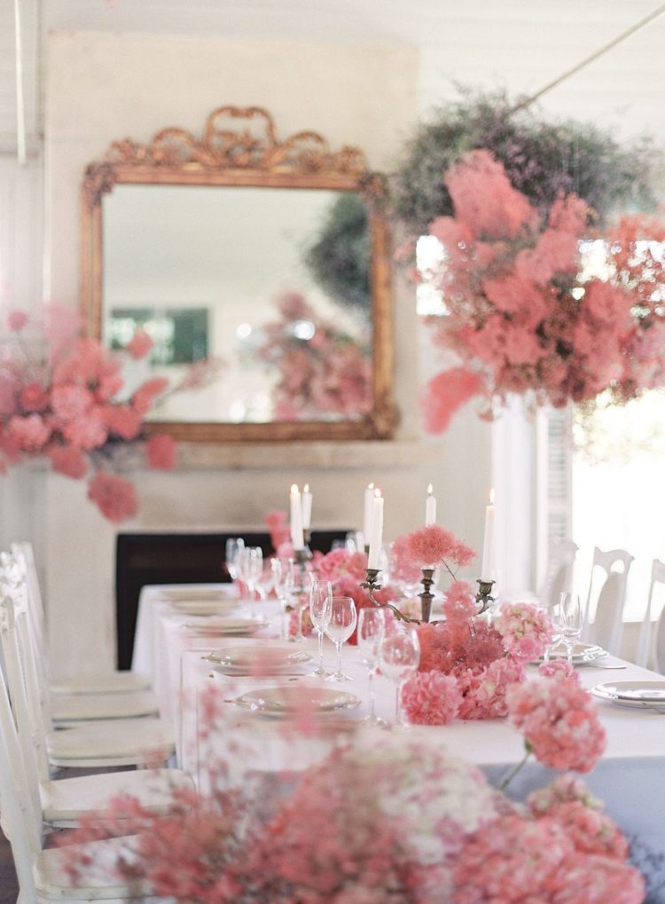 a refined wedding reception table with pink blooms and smoke bush on it and over it