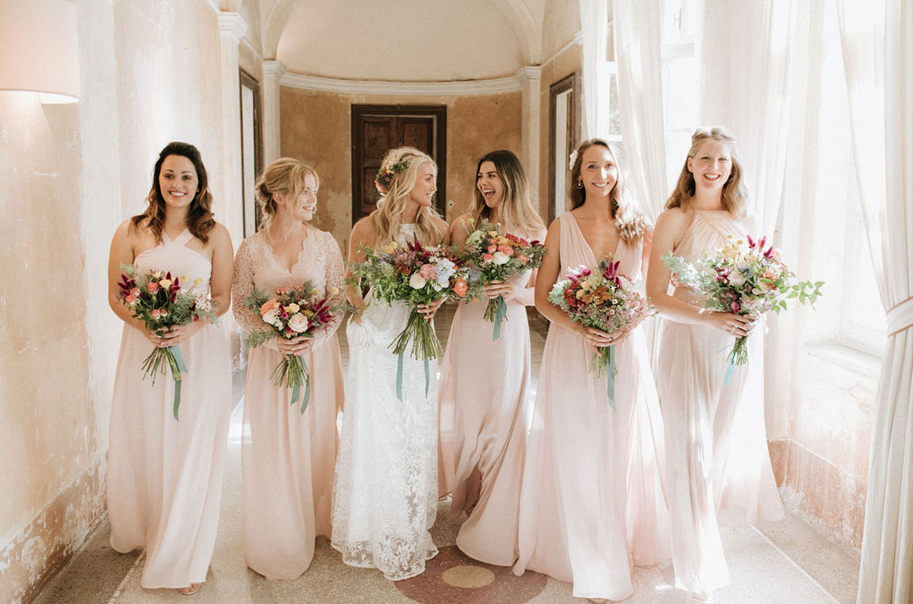 The bridesmaids were wearign mismatching blush maxi dresses and carrying bright bouquets