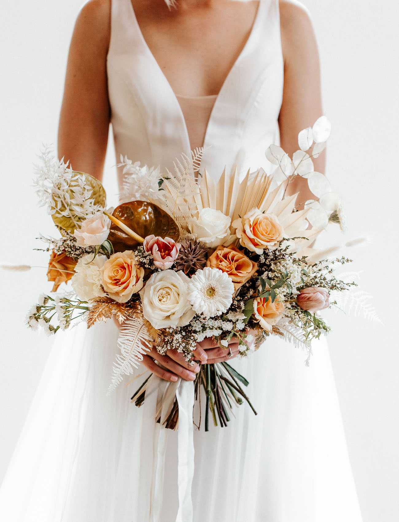 The wedding bouquet was done with peachy and pink blooms, fronds, greenery and lots of catchy details