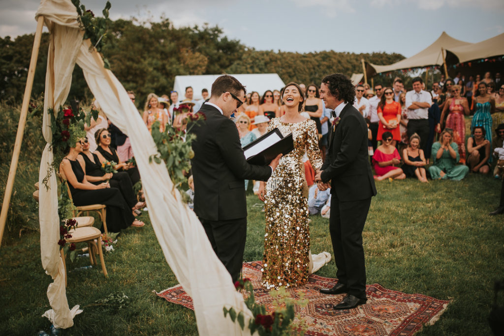 Everyone gathered in the back seaside garden and the ceremony space was done with a boho rug, greenery and some blooms
