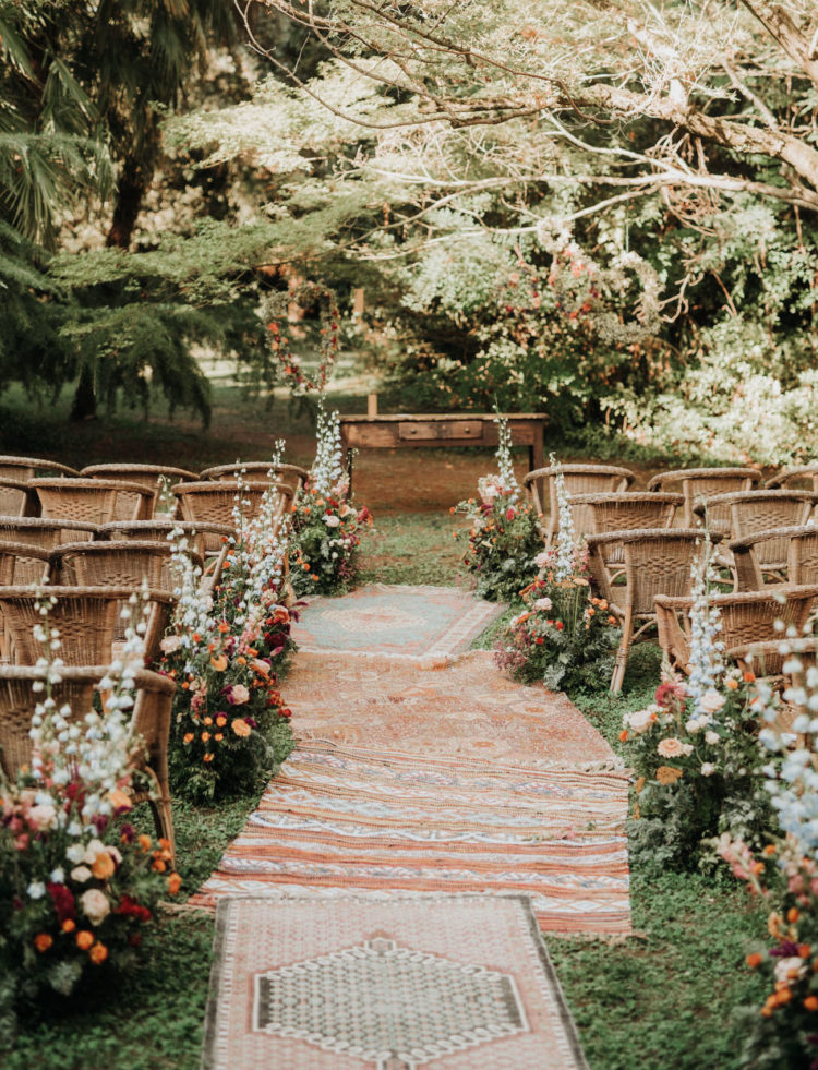 The wedding ceremony space was done super bright, with bold blooms, greenery and boho rugs