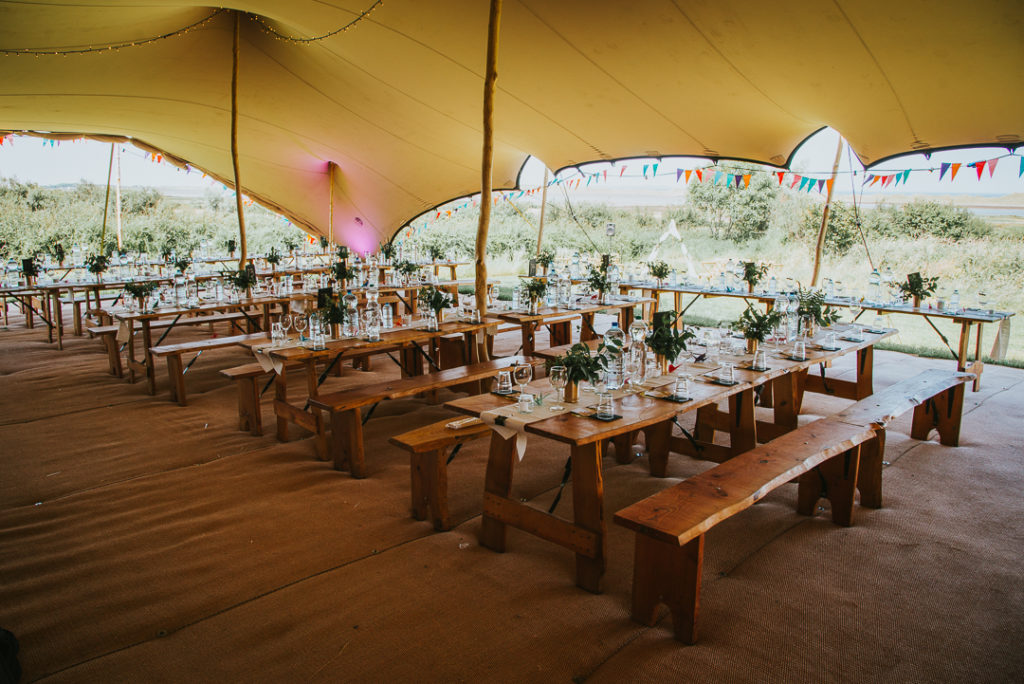 The reception was done under a large tent, with colorful buntings and wildflower centerpieces