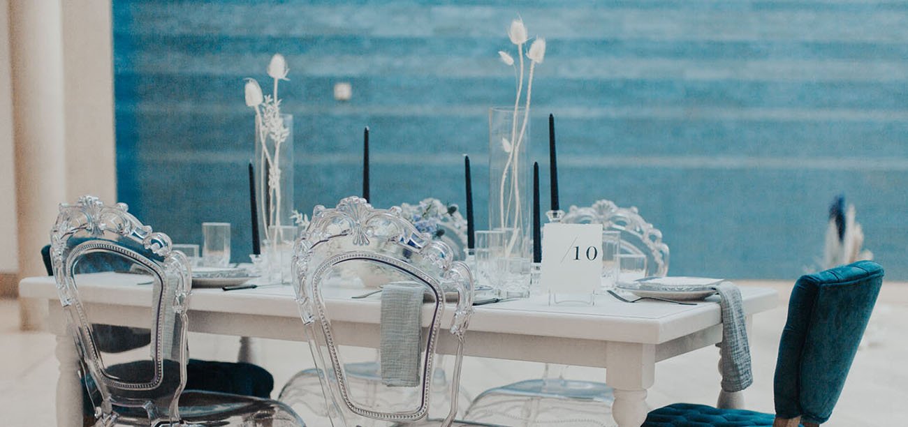 The wedding tablescape was done with black candles, dried white blooms and grasses, elegant chairs and grey linens