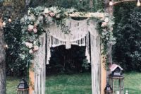 07 a gorgeous boho backyard wedding arch with macrame, greenery, pink and white blooms and oversized vintage candle lanterns