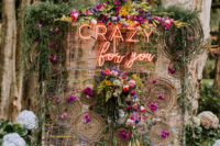 08 The wedding backdrop was done with colorful yarn and blooms, with a neon sign and greenery on top