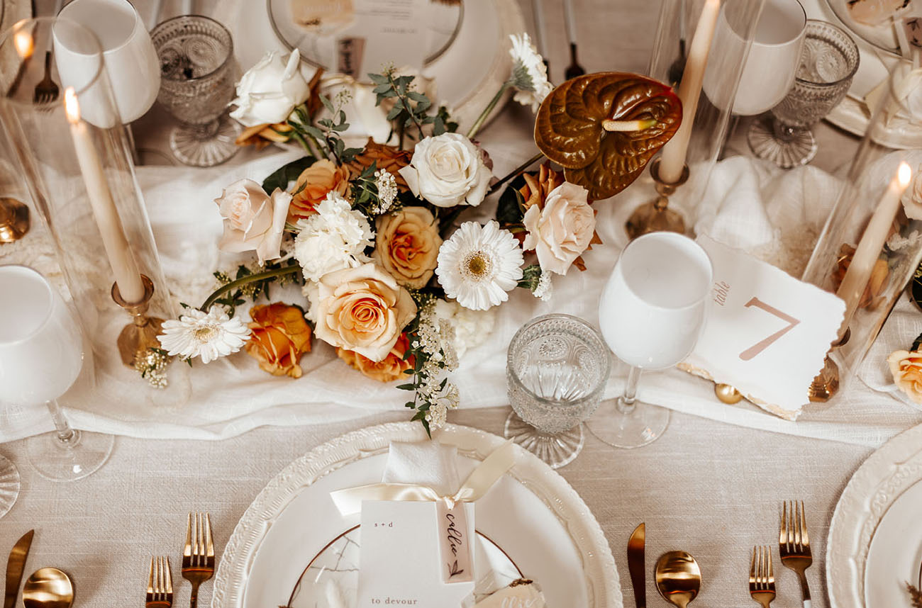 The wedding tablescape was done with peachy and gilded blooms, candles, copper cutlery and and other touches