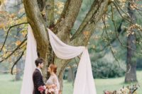 11 a simple wedding arch using a living tree and some airy white fabric with candles and fall leaves on the ground