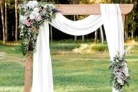12 an elegant rustic backyard wedding arch with airy fabric, pastel and white blooms, greenery and white candle lanterns