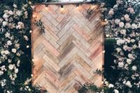 18 a boho backyard wedding backdrop of wood clad in herringbone patterns, with lush blush blooms and greenery around