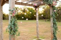 22 a rustic wedding chuppah with greenery, pink blooms and blooms hanging in bubbles over the space