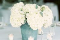 a galvanized bucket with white hydrangeas and candles is a cool rustic backyard wedding centerpiece