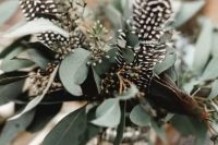 a natural boho wedding centerpiece of eucalyptus and feathers is a beautiful idea