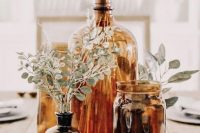 amber and brown glass bottles and jars with greenery and dried grasses is a cool and lovely wedding centerpiece