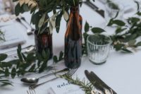 dark bottles with lush greenery and a greenery table runner will refresh any backyard wedding tablescape