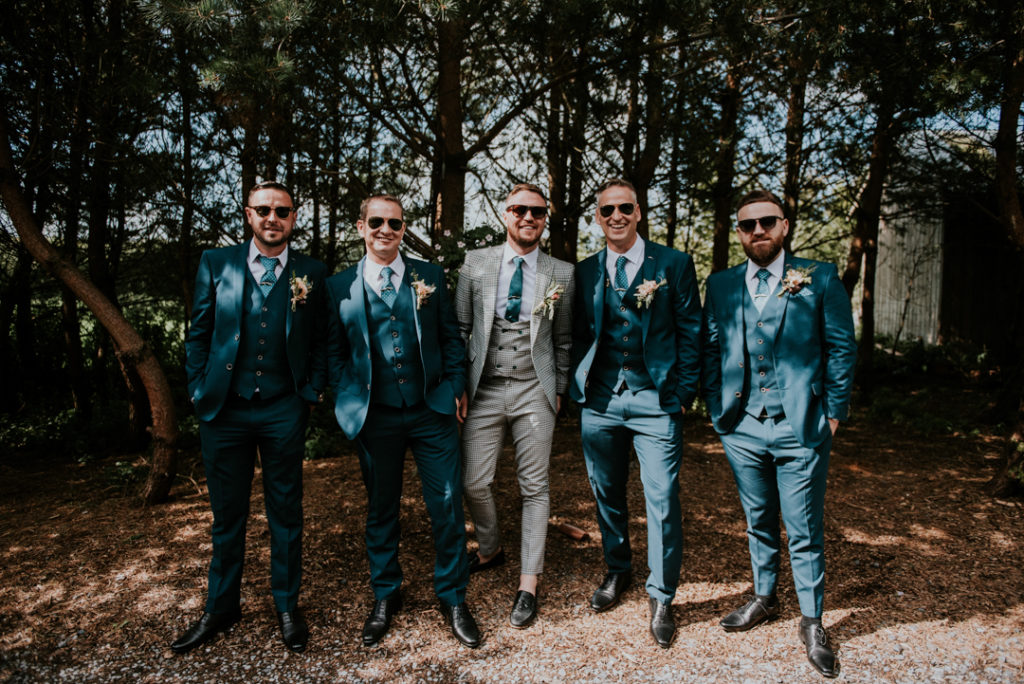The groom was wearing a plaid three piece suit, a blue tie and moccasins, the groomsmen were rocking navy three piece suits